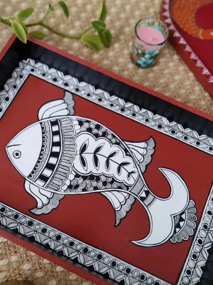 This hand-painted wooden tray features a fish motif in the traditional Madhubani style. It's a beautiful and functional piece, perfect for serving guests or as a decorative accent.