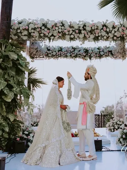 The Varmala exchange under a stunning floral arch, a classic and beautiful wedding moment.
