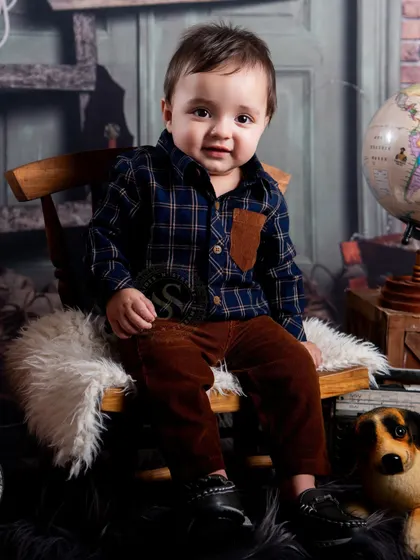A sweet, smiling portrait from our cowboy adventure set. The warm lighting and detailed background create a cozy and engaging atmosphere for this toddler's photo session.