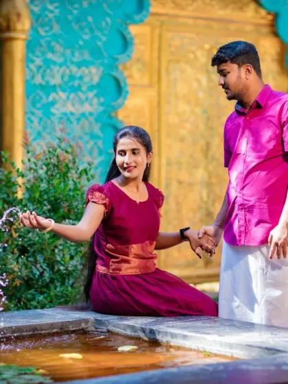 A playful moment by a fountain, with the couple sharing a laugh. Their traditional attire and the beautiful setting create a joyful pre-wedding photo.