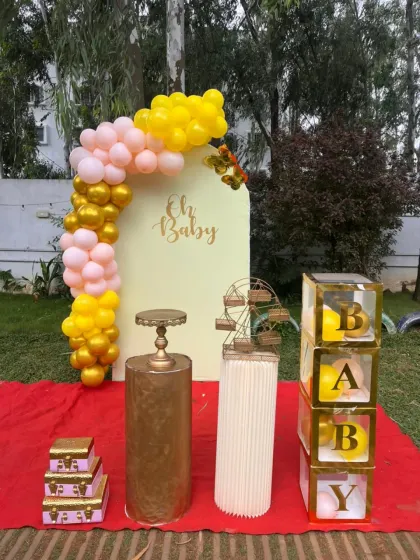 A modern and chic "Oh Baby" photo booth setup with a pastel balloon arch and transparent "BABY" display boxes.