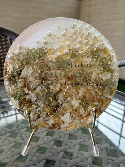 An 8-inch round display frame with preserved varmala flowers. The simple and elegant design, personalized with the couple's names, makes this a beautiful and timeless keepsake.