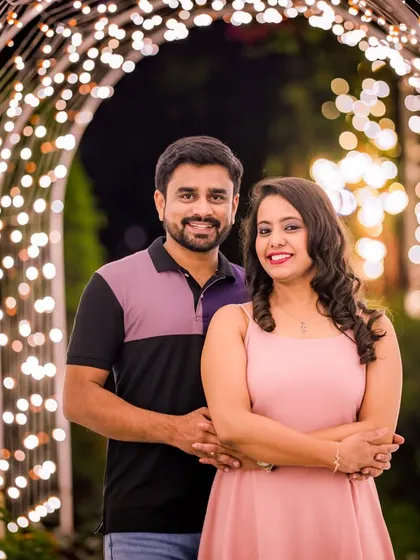 A classic, smiling portrait of a couple framed by the beautiful arch of fairy lights.
