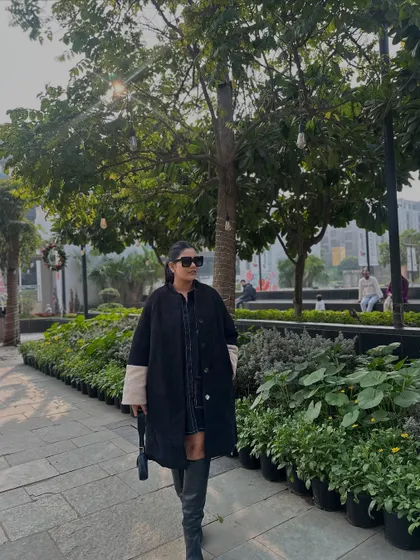 Walking through the park in my black coat and knee-high boots. It's a classic, sophisticated winter look.