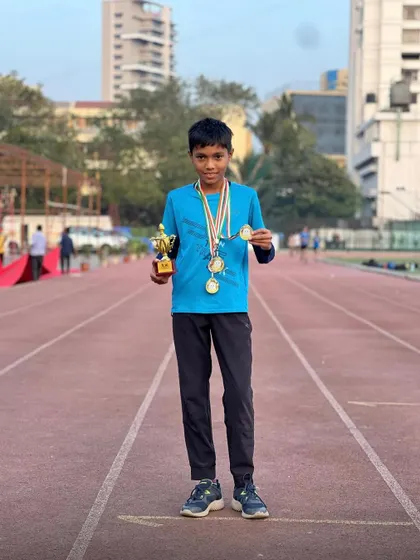 This young athlete proudly displays his medals and trophy on the track. This is what happens when potential meets dedication.