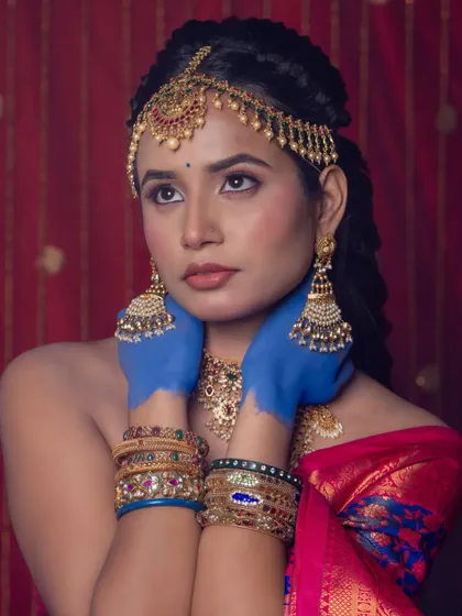 An artistic shot featuring our traditional matha patti, jhumkas, and layered necklaces against a vibrant red backdrop.