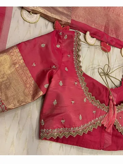 A detailed shot of the red blouse and saree, highlighting the scallop krosha tassels on the saree.