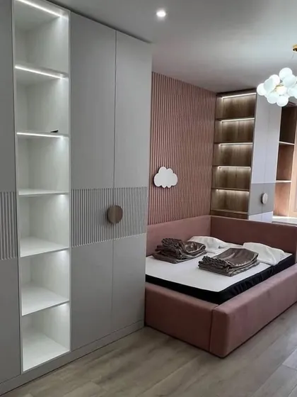 A bedroom wardrobe solution that combines closed storage with open, backlit shelving. This design is perfect for displaying decorative items while keeping clutter hidden away.