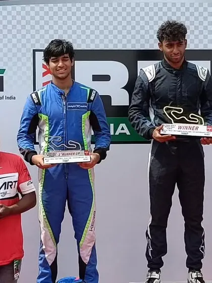 Our driver Rishon Rajeev on the top step of the podium, accepting his winner's trophy. This victory is a direct result of our structured coaching and elite technical support.