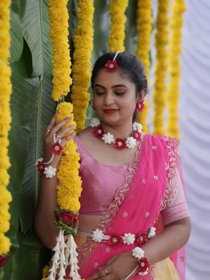 A beautiful bride posing with marigold garlands during her Haldi ceremony, with a simple yet elegant backdrop.
