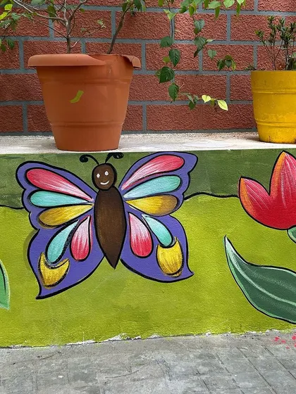 A colorful butterfly and flower painted on the lower part of the school wall, where the kids can see them up close.