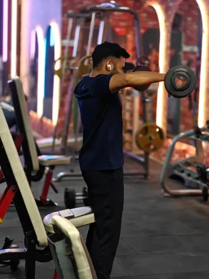 A client performs a dumbbell front raise, an essential exercise for developing strong and defined shoulders. We focus on controlled movements for maximum impact.