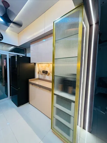 A close-up of a custom storage solution. This tall pantry unit features a ribbed glass shutter with a brass-finished frame, providing elegant and accessible storage for kitchen essentials.