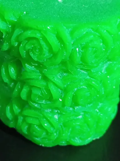 A side view of the green pillar candle with rose carvings. The texture and detail make it much more than just a source of light.
