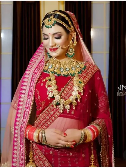 A regal bride with her hair in a classic bun, perfectly styled to accommodate a heavy dupatta and elaborate jewelry. This look is fit for a royal wedding.