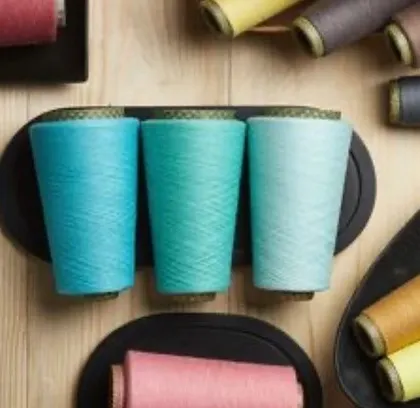 An artfully arranged flat-lay of various yarn cones on wooden and black trays. This shot serves as a beautiful abstract representation of a brand's color story.