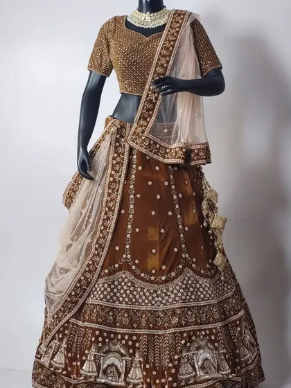 A unique and elegant brown bridal lehenga with intricate doli embroidery on the border. Paired with a simple choker, this outfit is available for rent for your wedding or pre-wedding shoots.