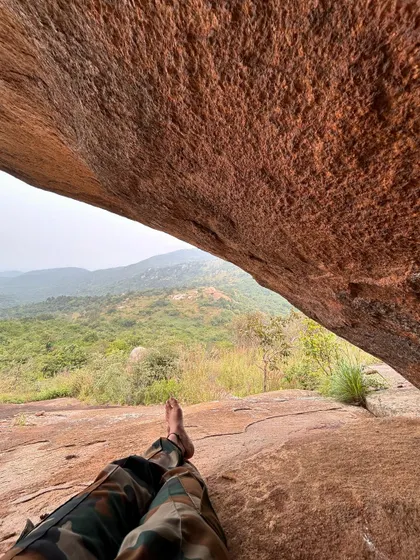 Taking a break and enjoying the view from a cave-like rock formation during the Skandagiri trek. It's a beautiful and moderately challenging hike near Bangalore.