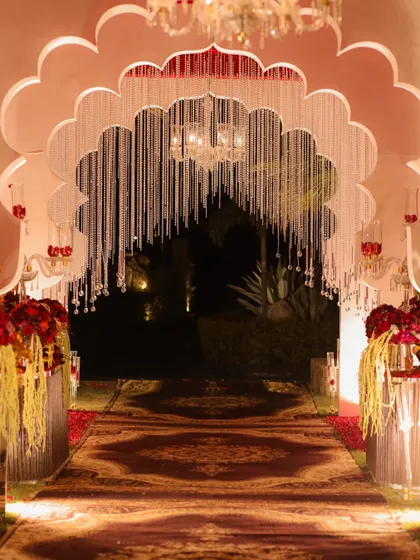 The grand entrance to the wedding, featuring a scalloped arch with hanging crystal strings. This sets a majestic tone, leading guests down a custom-printed carpet to the main event.