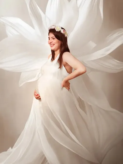 An ethereal portrait in a flowing white gown. The fabric appears to float like wings, giving this mom-to-be an angelic and graceful presence in her maternity photo.