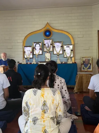 A Sunday Satsang meditation session in progress. Even in a full room, a palpable stillness descends as everyone turns their attention inward, creating a shared experience of peace.