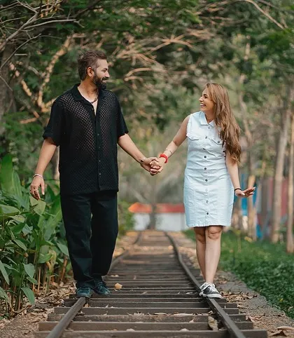 Nishant and Jaspal walk hand-in-hand along the railway tracks, sharing a smile. This candid shot captures a simple, happy moment on their journey together.
