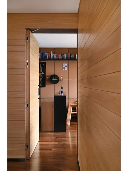 A peek into the lounge room, a perfect bachelor pad or man cave. The space is defined by wood-paneled walls and a custom bar.