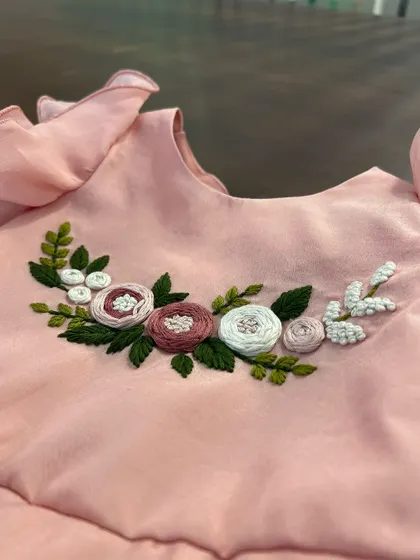 Delicate flower blossoms hand-embroidered with thread, brightening up a lovely pink top for a little one.