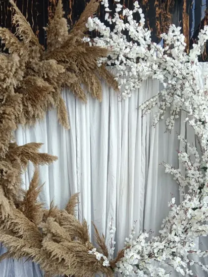 A different angle of the pampas and blossom backdrop, showing how the contrasting elements create a visually interesting frame against a simple white curtain.