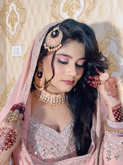 A soft and romantic look for a Nikah ceremony. The makeup features pink shimmery eyeshadow and a matching lip colour, complementing the delicate pink outfit and henna.