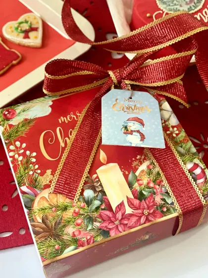 A beautifully packaged box of our hand-decorated Christmas cookies. The festive box is tied with a glittery red ribbon and a snowman gift tag, making it a perfect ready-to-give present.