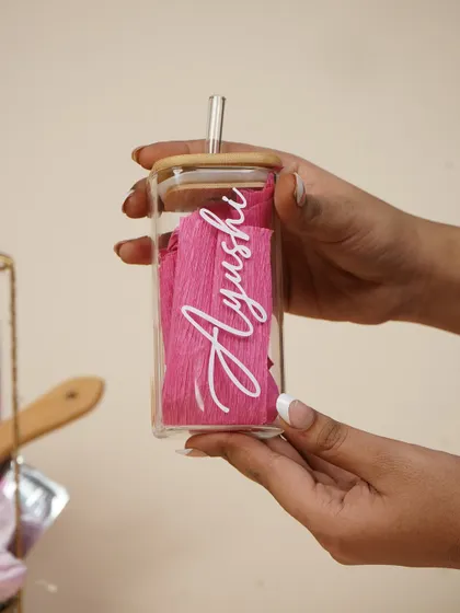 A stylish glass tumbler with a bamboo lid and straw, personalized with her name. It's a trendy and practical gift she can use every day.