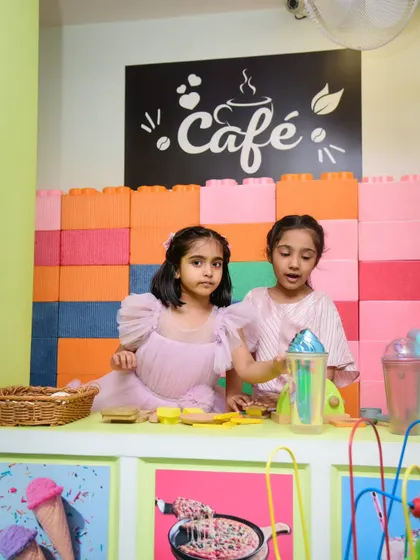 Let's cook some fun! Two girls work together in the pretend cafe, whipping up imaginary treats.