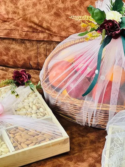 A close-up showing the textures and details of the trousseau packing. The combination of the wooden dry fruit box and the wicker fruit basket is rustic yet elegant.