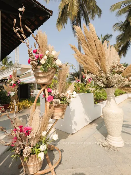 A detailed look at the rustic floral arrangements used to decorate the event entrance. We used tiered wicker baskets to hold arrangements of pampas grass and fresh flowers, adding texture and natural charm.