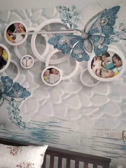 A custom 3D wallpaper featuring a large blue butterfly and photo frames, designed to incorporate personal family pictures directly into the wall art.