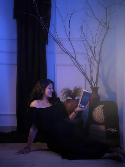 A creative and moody shot with cool blue lighting. The mother-to-be is captured in a quiet moment, reading a book, which adds a personal storytelling element.