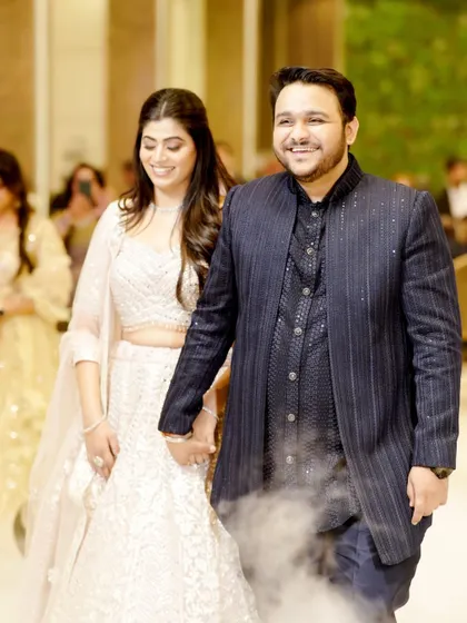 The couple's grand entrance at their engagement party, walking hand-in-hand through theatrical smoke.
