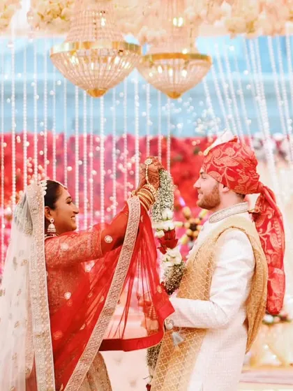 A candid moment from a cross-cultural wedding ceremony, capturing the couple's interaction under a beautifully decorated mandap.