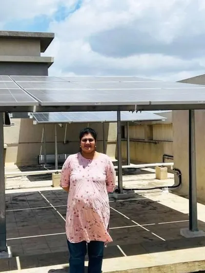 A proud resident of Sattva Aspira Housing Society in Bangalore stands with her new rooftop solar installation.