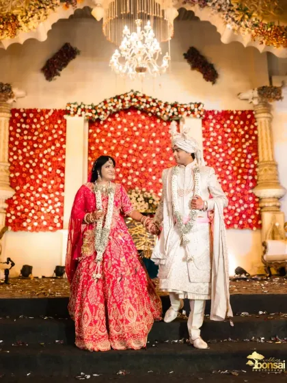 A grand portrait of the couple on their wedding stage, against a backdrop of red roses.