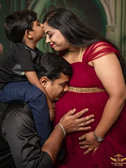 The whole family showing love for the baby on the way. A son's kiss for mom and a dad's ear to the bump make this a perfect family portrait.