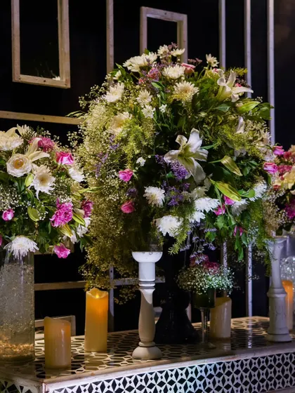 Large, lush bouquets of white and purple flowers sit atop a patterned console table, adding a touch of classic beauty to the modern decor.
