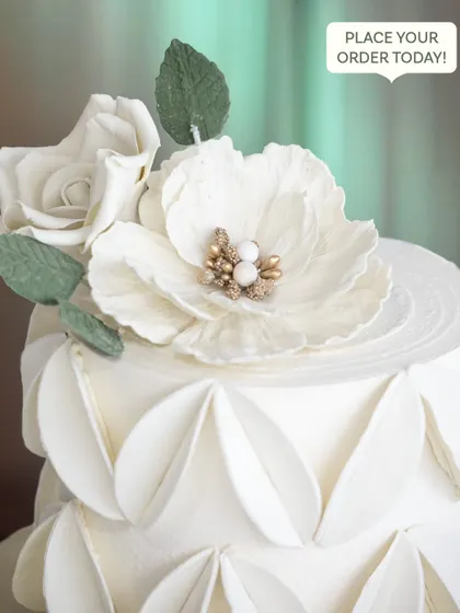 A close-up of the exquisite, handcrafted white sugar flower, showing the delicate details in its center.