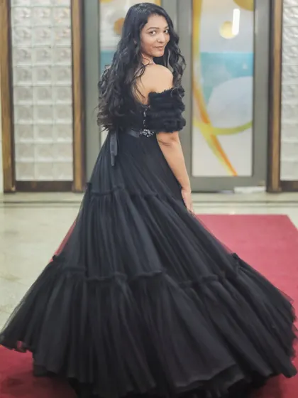 A back view of the client in the black tiered gown, showing its full, dramatic skirt.