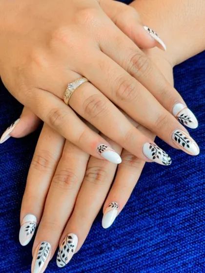 A striking black and white botanical design. The detailed leaf patterns were carefully hand-painted on a solid white base, creating a beautiful contrast on these almond-shaped nails.