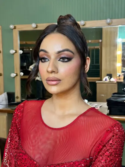 This unfiltered shot shows the complete look with the high bun. The makeup is glamorous yet elegant, perfect for a red-themed party.