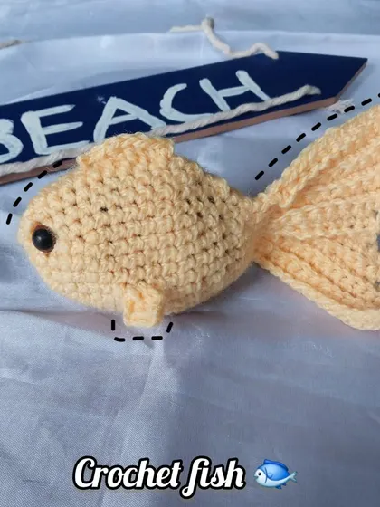 A side profile of the crochet fish, highlighting its 3D shape and cute little eye.