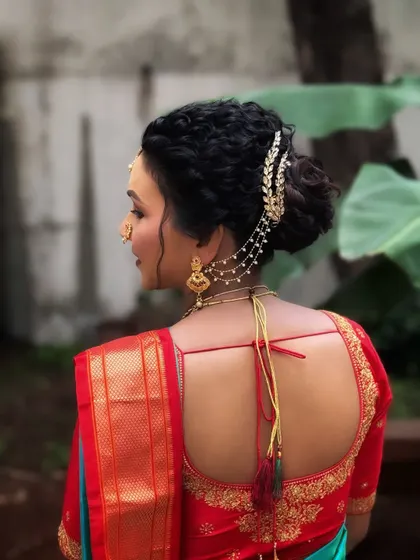 A North Indian bride embracing Maharashtrian tradition. This hairstyle is a modern take on a traditional bun, with intricate braids and an elegant hair accessory.