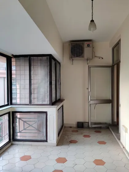 The 'before' view of the old balcony, with its dated hexagonal tiles and heavy aluminum-frame windows.